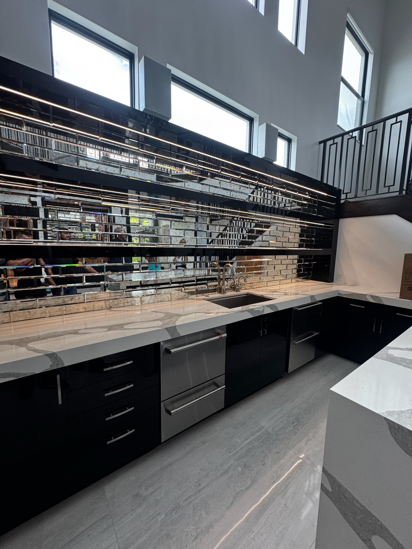 Modern kitchen with mirrored backsplash and marble counters